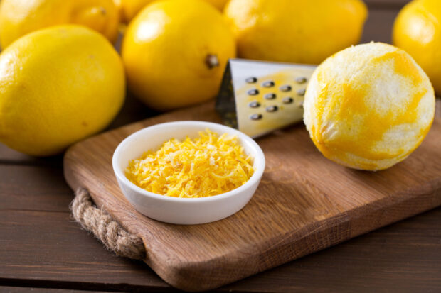 Limoni su tagliere. Un limone è privato della scorza, che sta sul tagliere in una scodella