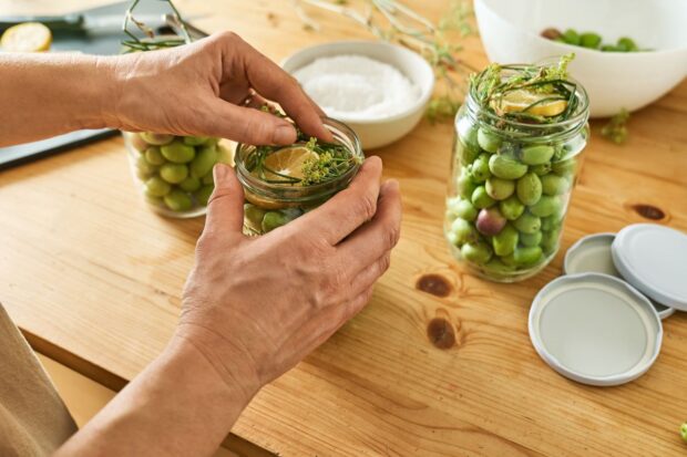 Olive verdi che vengono riposte in recipienti per essere conservate