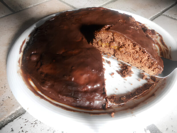 Sacher torte senza glutine, ed una sua fetta, su un piatto mentre viene tagliata