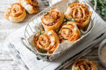 Rotelle di pasta sfoglia da aperitivo con prosciutto di Praga, granella di mandorle e petto di pollo