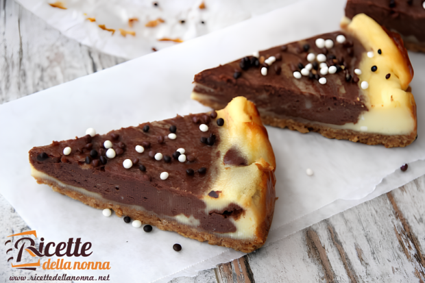 Due fette di cheesecake al cioccolato cotta con base di biscotto e crema al cioccolato, decorate con praline di cioccolato
