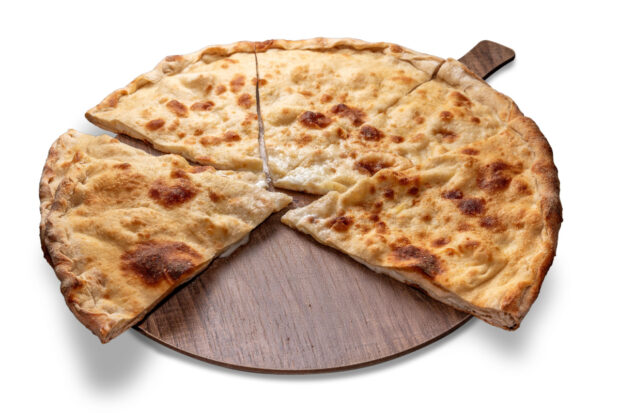 Schiacciata ripiena di prosciutto, mozzarella e stracchino su tagliere di legno, tagliata a spicchi