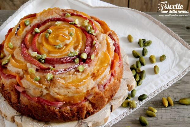 Torta intera alle pesche su un piatto, decorata con pinoli