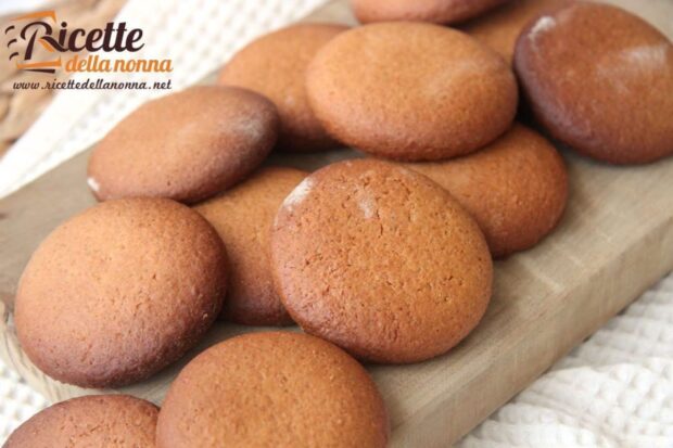 Biscotti integrali rotondi con miele e cannella su un tagliere di legno