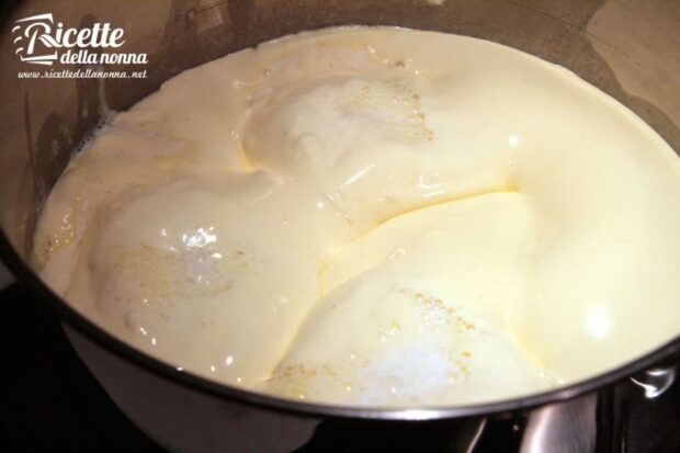 Crema pasticcera in cottura che sobbolle e si addensa in una casseruola sul fuoco.