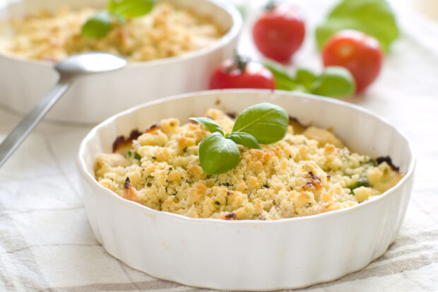 Crumble salato in una pirofila bianca, decorato da basilico
