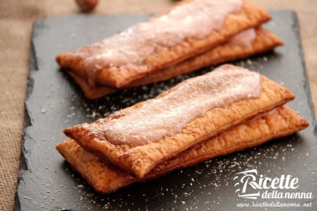 Dolce millefoglie fatto con pasta sfoglia pronta, farcito da una crema di yogurt e Nutella tra gli strati e coperto da cocco rapè, servito su un vassoio nero