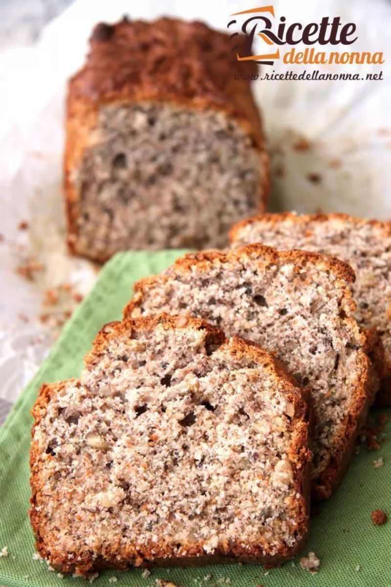 Tre fette di un plumcake fatto con yogurt, miele, noci e farina integrale, su una tovaglia verde. Il resto del plumcake tagliato è sullo sfondo