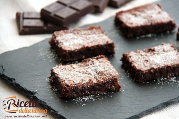 Quattro fette di Torta Nera su un rialzo nero. Cioccolato fondente sullo sfondo
