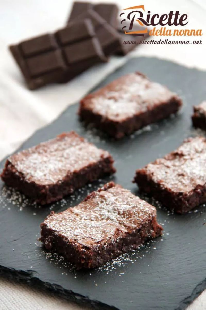 Quattro fette di Torta Nera su un rialzo nero. Cioccolato fondente sullo sfondo