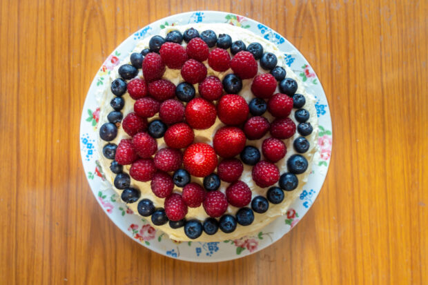 Torta crema e cioccolato guarnita con frutti di bosco