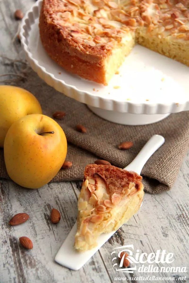 Fetta di torta plumcake fatta con le mele. 2 mele alla sinistra e il resto della torta sullo sfondo