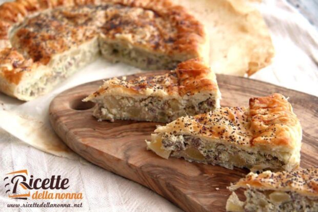 Tre fette di Torta salata broccoli ricotta e salsiccia su un tagliere di legno. Dietro il resto della torta salata