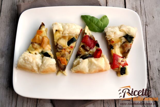Quattro fette di torta salata con verdure grigliate su un piatto