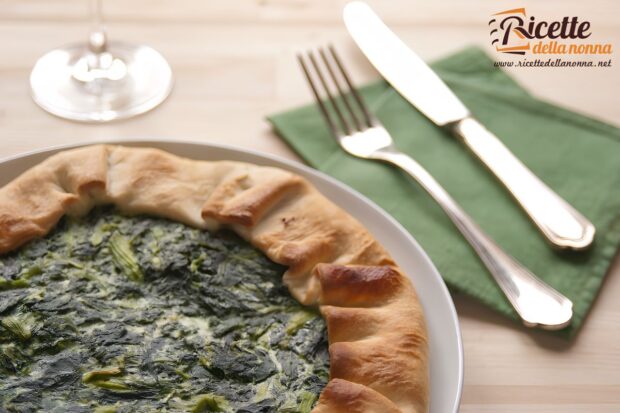 Torta verde, torta rustica di brisée con spinaci su un piatto accanto a forchetta e coltello sopra un tovagliolo verde