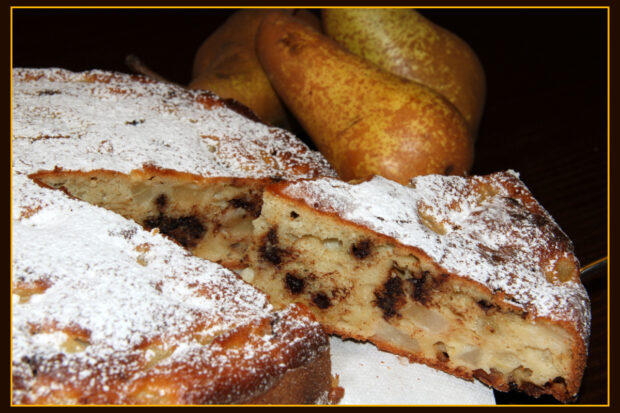 Torta yogurt cioccolato e pere, con una fetta tagliata e tre pere sullo sfondo