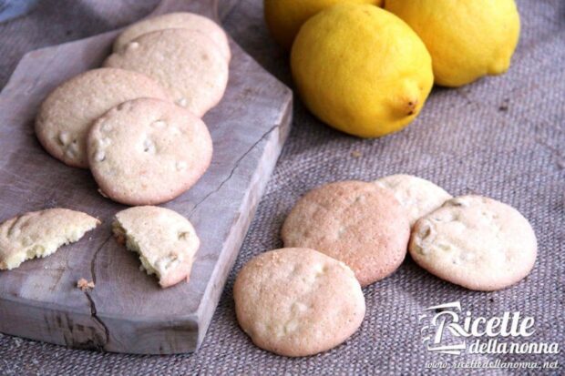 Biscotti al limone candito su un tagliere di legno, accanto a dei limoni