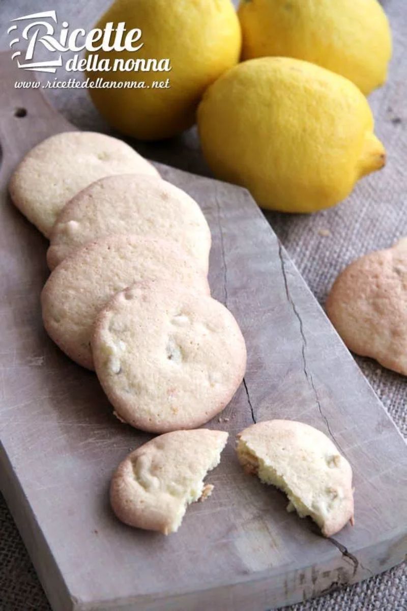 Delizie al limone, biscotti al limone candito su un tagliere di legno, accanto a dei limoni