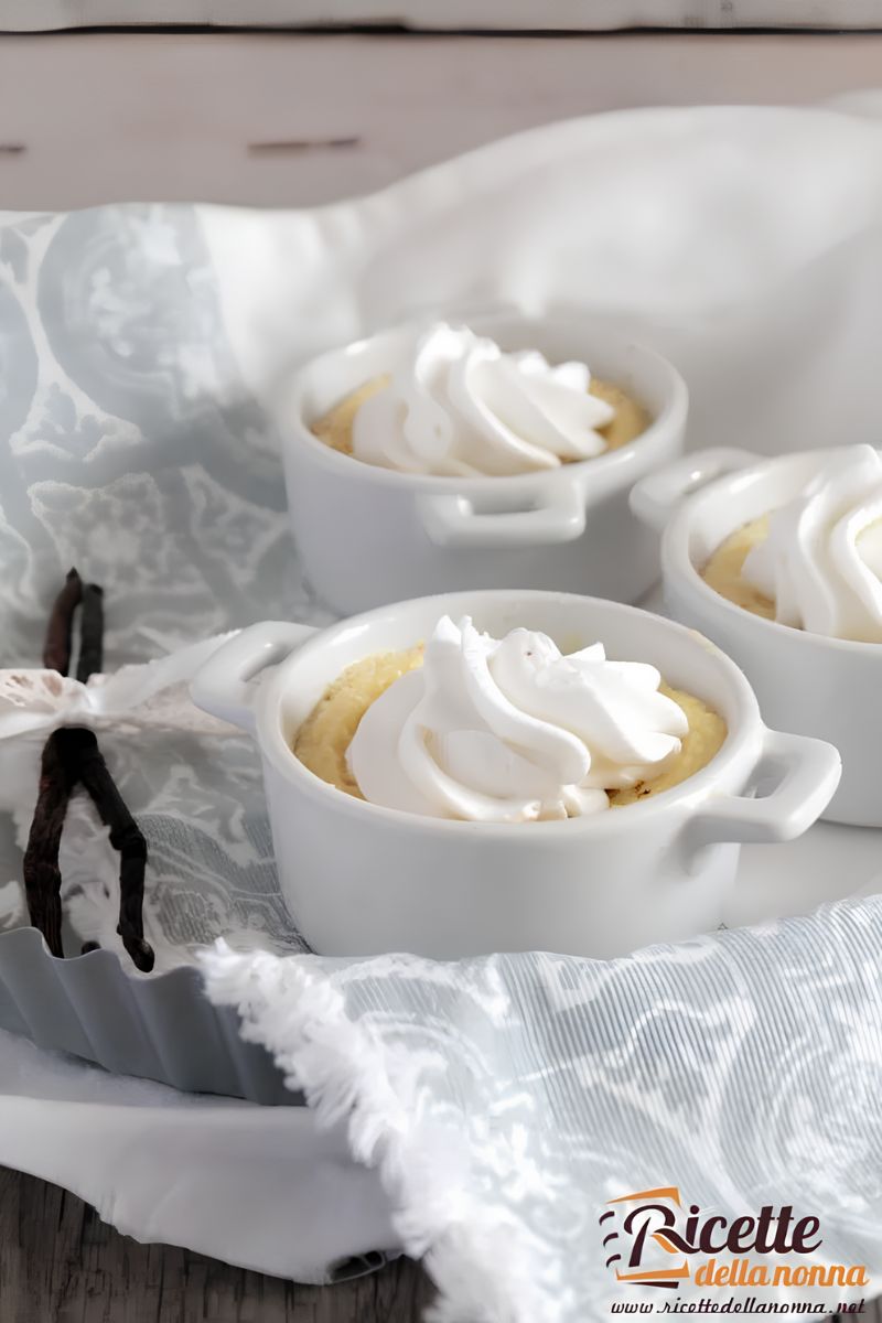 Tre dessert light alla vaniglia e latte in piccole coppette bianche, con sopra della panna. Primo piano