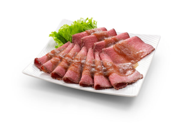 Fette di roast beef messe su un piatto bianco con sopra della salsa