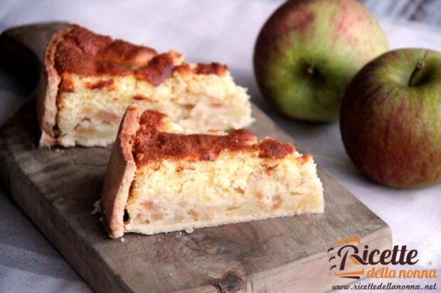 Due fette di torta di mele meringata su tagliere di legno. Due mele verdi sullo sfondo